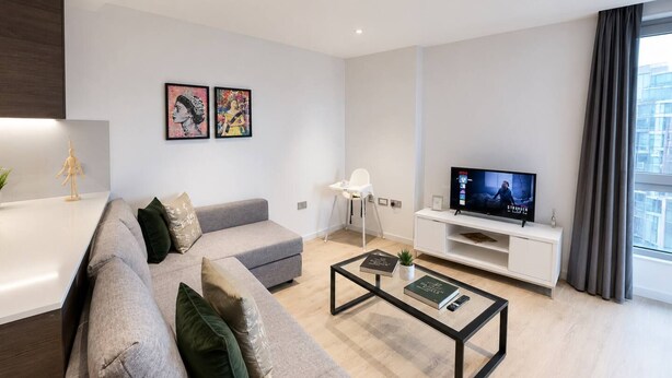 A modern living room with a grey sofa, a coffee table, a TV, and artwork on the wall. - Kings Cross Apt W/ Balconies | st pancras & camden (London)