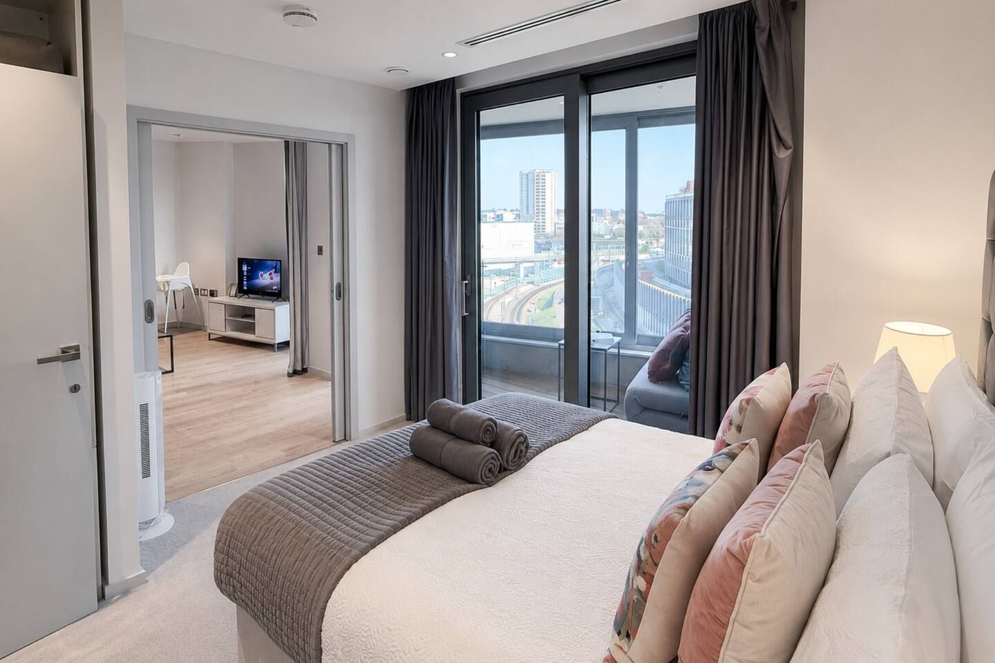 Una habitación de hotel moderna con una cama grande, televisión y vistas a la ciudad.