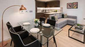 A modern living room with a glass dining table, black chairs, a grey sofa, and a coffee table. - Kings Cross Apt W/ Balconies | st pancras & camden (London)