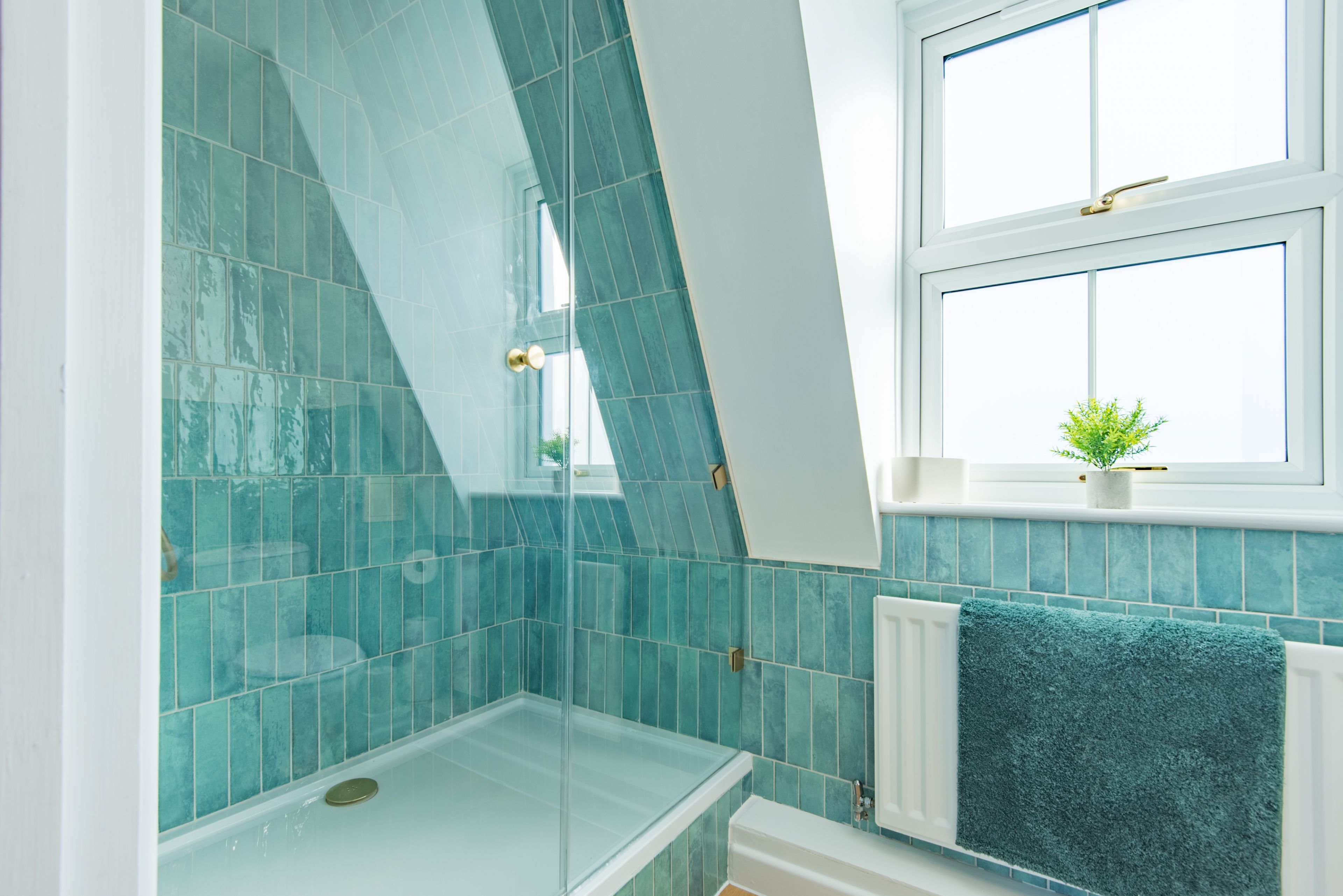 Un baño con cabina de ducha de vidrio, ventana con vistas y un perchero para toallas.