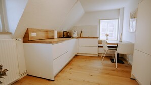 Una cocina con encimera de madera, armarios blancos y un comedor con una silla.
