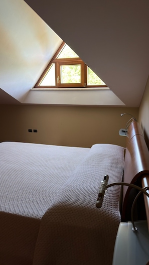A bedroom with a skylight, a bed, a bedside table, and a lamp. - Villa Aresini – Exclusive Residence (Montemiletto)