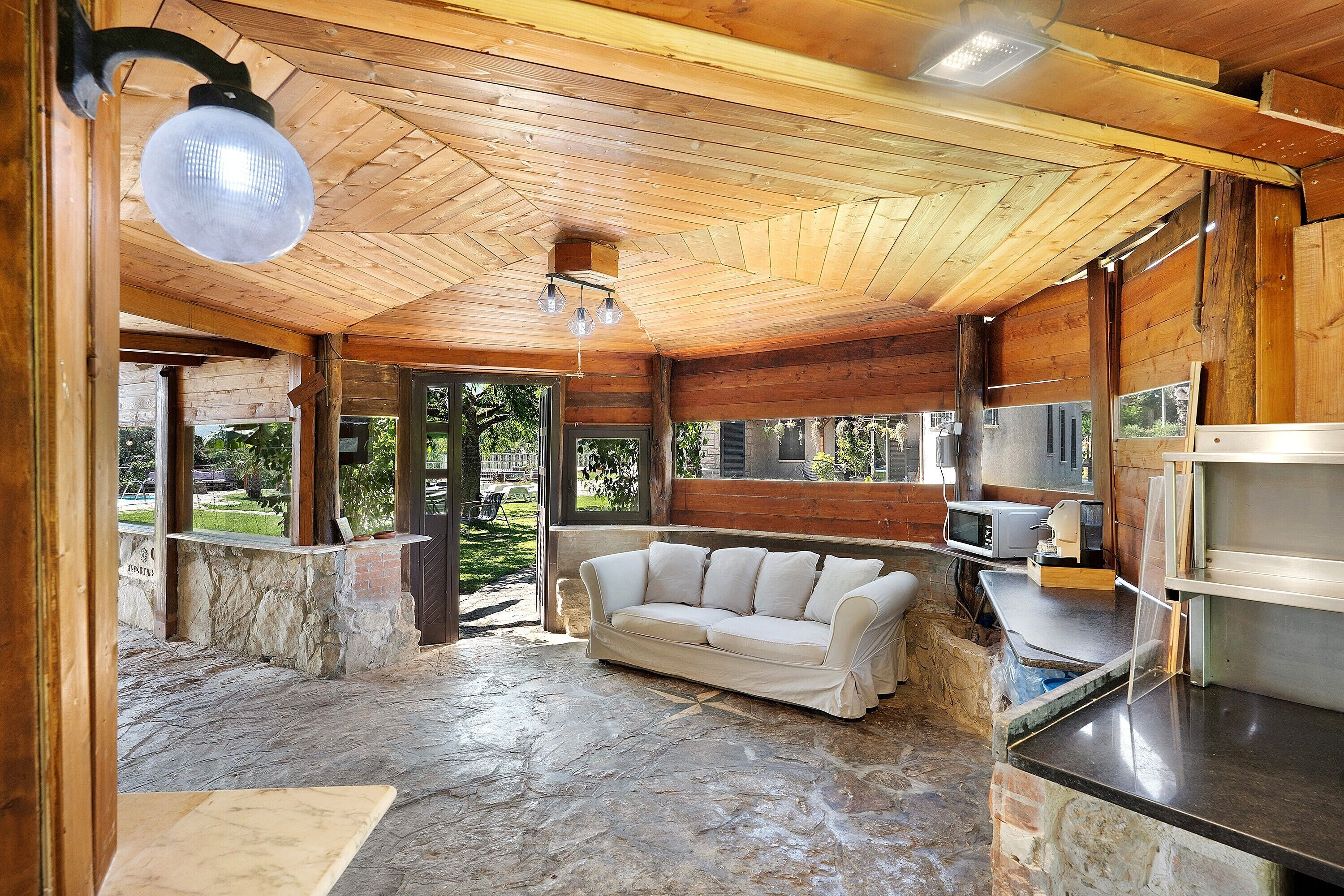 A wooden interior with a stone floor, a white sofa, and a kitchen area with appliances.