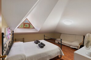 Un dormitorio con cama, ventana, ventilador y sofá.