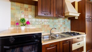 Une cuisine avec des meubles en bois, une cuisinière à gaz, un lave-vaisselle et un dosseret carrelé.