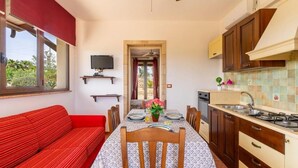 Une cuisine compacte avec un coin repas, un téléviseur fixé au mur et un canapé rouge.