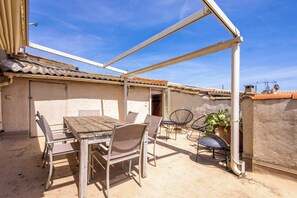 Eine Außenpatio mit Tisch und Stühlen, einer Pergola und einem Blumentopf.