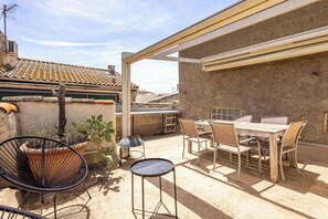 Eine Terrasse mit Tisch, Stühlen und einem Topfpflanzen.