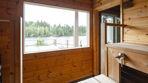 A wooden cabin interior with a large window offering a view of a lake and forest. - Lakefront Holiday Villa - Traditional Finnish sauna & outdoor jacuzzi (Uurainen)