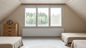 A bedroom with a sloped ceiling, a large window with a view of trees, a wooden dresser, and two beds. - Lakefront Holiday Villa - Traditional Finnish sauna & outdoor jacuzzi (Uurainen)