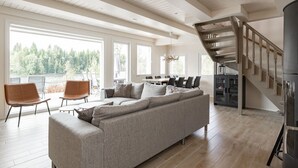 A spacious living area with a large sofa, a dining table, and a staircase. - Lakefront Holiday Villa - Traditional Finnish sauna & outdoor jacuzzi (Uurainen)