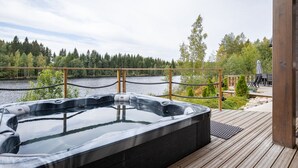 A hot tub on a wooden deck with a view of a lake and forest. - Lakefront Holiday Villa - Traditional Finnish sauna & outdoor jacuzzi (Uurainen)
