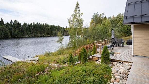 A lakeside deck with outdoor furniture, a dock, and a building with a dark roof. - Lakefront Holiday Villa - Traditional Finnish sauna & outdoor jacuzzi (Uurainen)