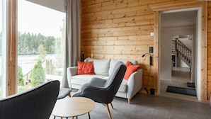 A cozy room with a sofa, chairs, a small table, and a view of a forest through large windows. - Lakefront Holiday Villa - Traditional Finnish sauna & outdoor jacuzzi (Uurainen)