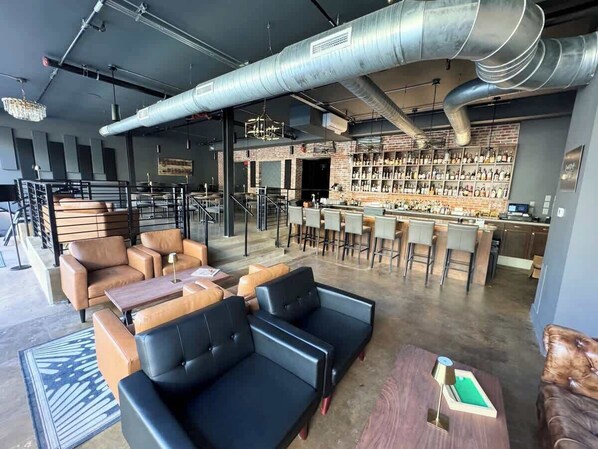 A bar area with seating, a kitchen, and a display of bottles.