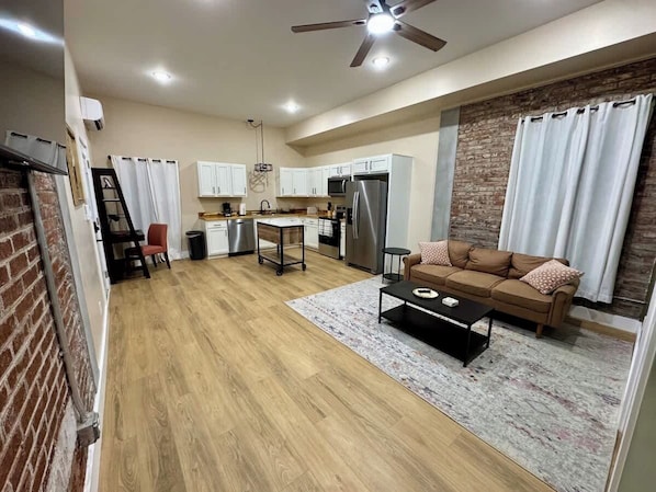 A modern kitchen with white cabinets, a stainless steel refrigerator, and a dining area with a wooden table and chairs.