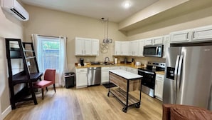 A compact kitchen with white cabinets, a stainless steel refrigerator, a microwave, and a dishwasher.