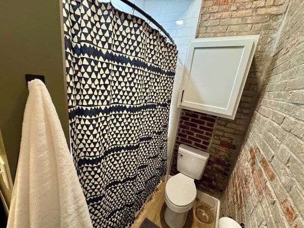 Un bagno con una tenda da doccia fantasia, un water e un armadietto bianco.