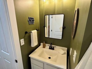 A bathroom with a sink, mirror, towel rack, and a sign that says 'WASH YOUR HANDS'. - Modern Boho Getaway 1BR Apartment By KeenStays (Cape Girardeau)