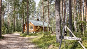 Une cabane au milieu d’une forêt, accessible par un sentier de terre.