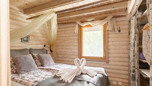 A cozy log cabin bedroom with a bed, a window, and a decorative towel arrangement.