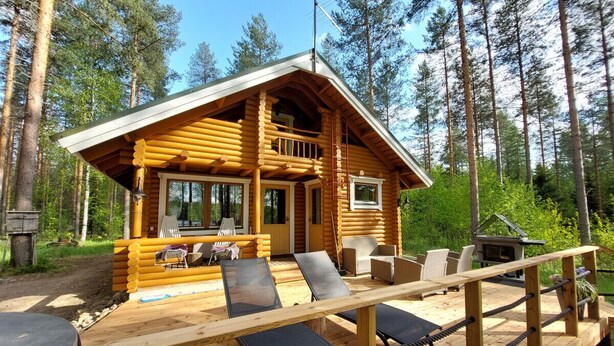 Une cabane en rondins dotée d’une terrasse, d’un espace salon extérieur et d’une cheminée.