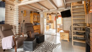 A log cabin interior with a living area, kitchen, and a television mounted on the wall.