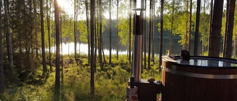 A hot tub in a forest with a view of a lake.