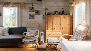A cozy cabin interior with a sofa, wicker chairs, a wooden cabinet, and wall art.
