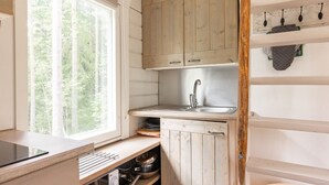 A kitchen with wooden cabinets, a stainless steel sink, and a window with a view of trees.