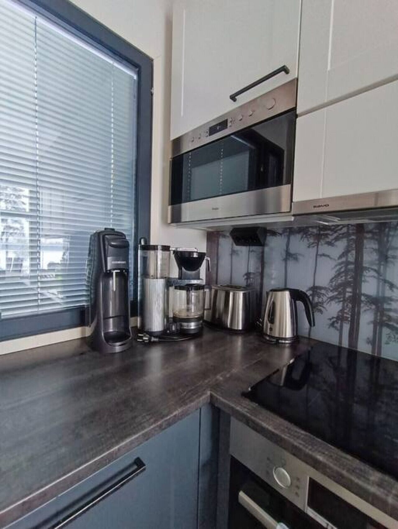 Uma cozinha moderna com micro-ondas embutido, máquina de café, chaleira e torradeira.