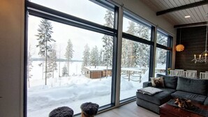Una sala de estar moderna con ventanas amplias, un sofá gris y una mesa de centro de madera.