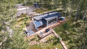 Una cabaña moderna con terraza, ventanas amplias y un panel solar.