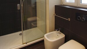 A bathroom with a glass-enclosed shower, a bidet, and a toilet. - Apartment with 2 double bedrooms (Roma)
