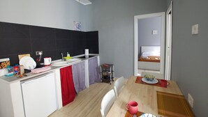 A compact kitchen with a sink, a small refrigerator, and a dining area with a table and chairs. - Apartment with 2 double bedrooms (Roma)