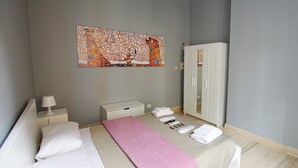 A bedroom with a bed, a bedside table, a wardrobe, a wall art piece, and a pink blanket. - Apartment with 2 double bedrooms (Roma)