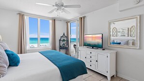 Ein Schlafzimmer mit einem Bett, einem Fernseher, einem Deckenventilator und Blick aufs Meer.