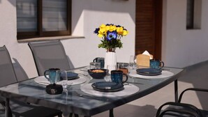 Une table en verre avec des assiettes bleues, un vase rempli de fleurs jaunes et une fenêtre en arrière-plan.