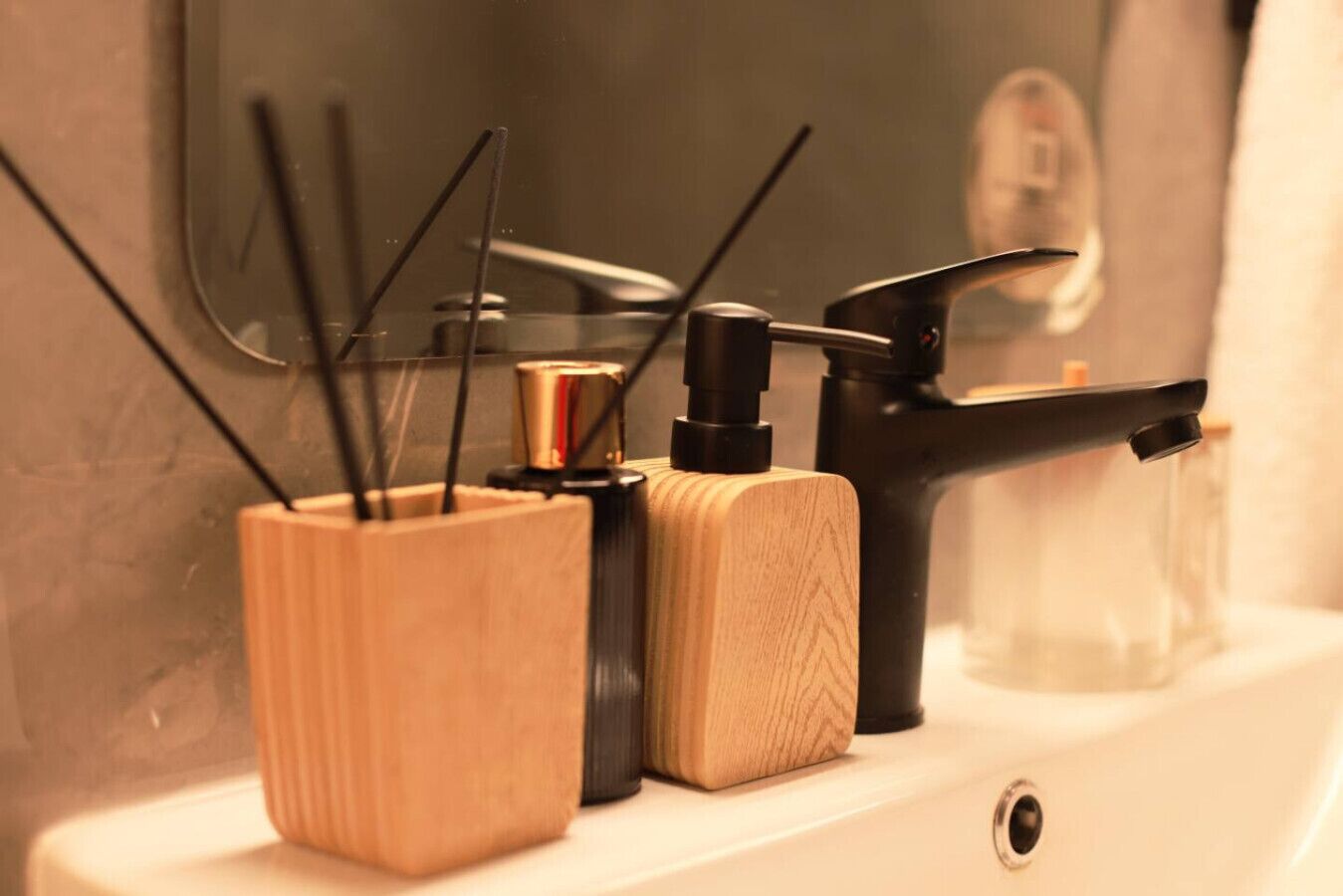 Un baño con un lavamanos, un grifo y dos recipientes de madera con objetos negros en su interior.