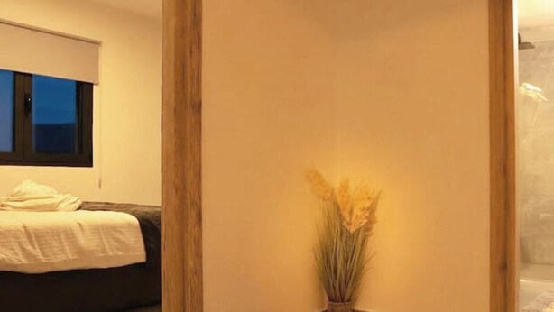 Une pièce avec un lit, une fenêtre et un vase contenant des plantes séchées.