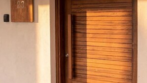 Une porte en bois avec des lattes horizontales, une petite boîte aux lettres et une plaque numérotée fixée au mur.