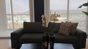 Een moderne woonkamer met een bank, een salontafel en twee potplanten.