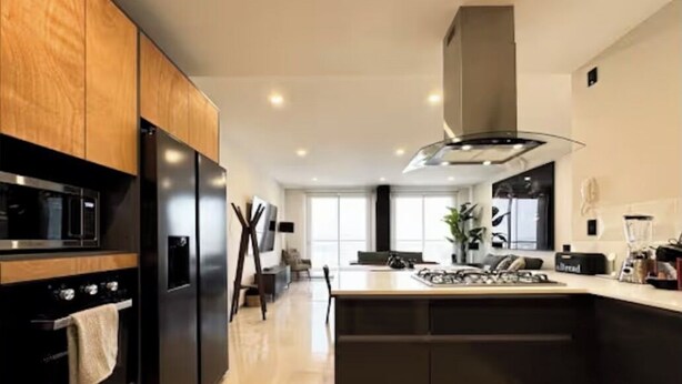 Een moderne keuken met een centraal eiland, een ingebouwde oven en roestvrijstalen apparatuur.