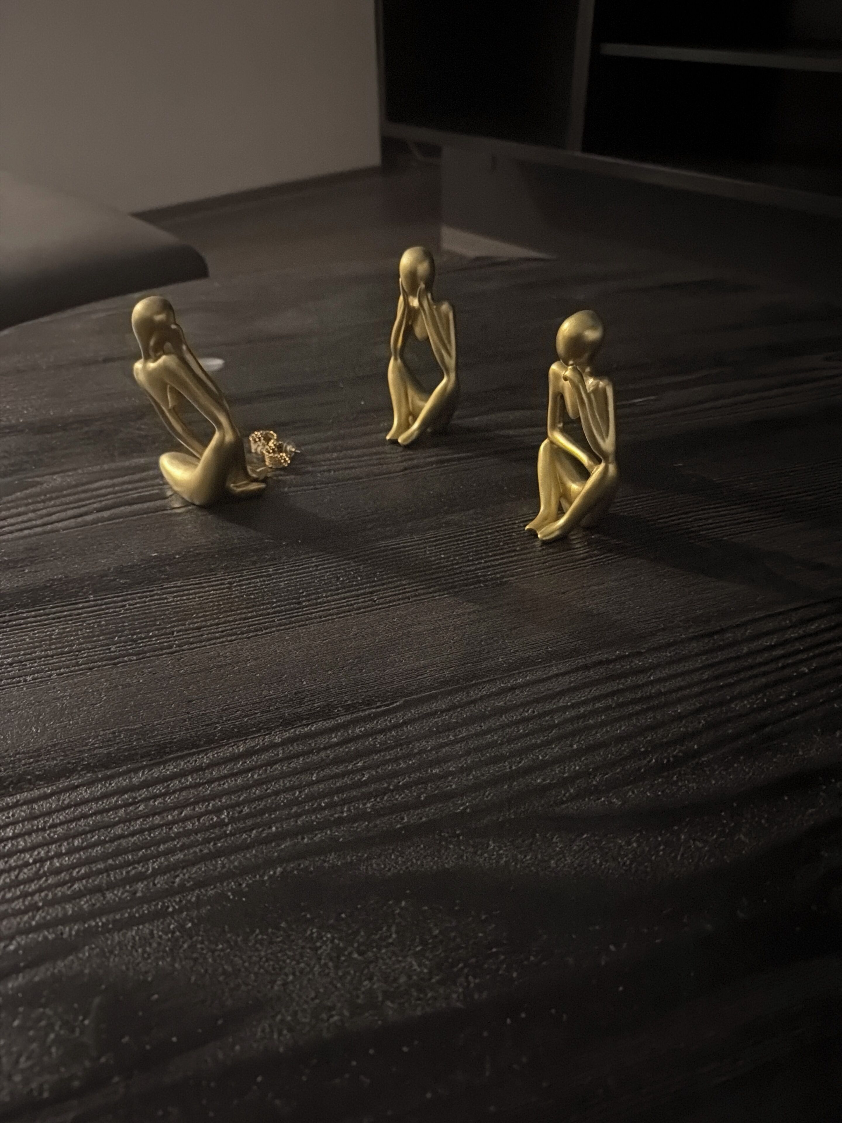 Three golden statues on a textured black surface.
