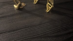 Drie gouden beelden op een gestructureerd zwart oppervlak.