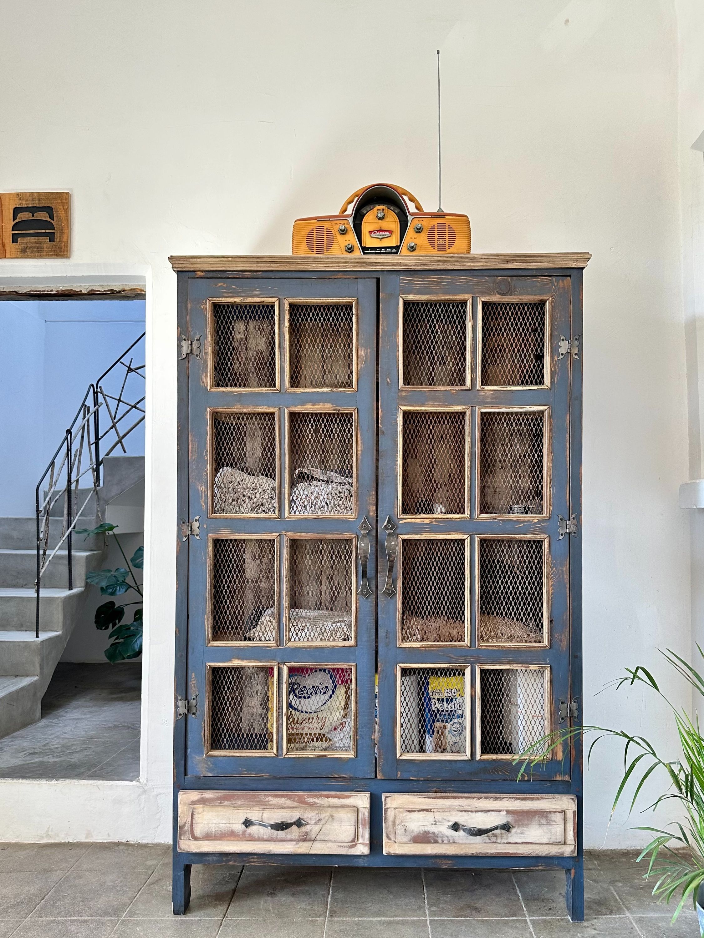 A blue cabinet with multiple drawers and a radio on top.