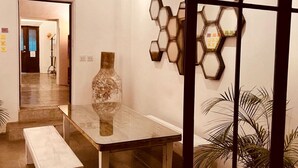 Ein modernes Interieur mit einer hängenden Leuchte, einer sechseckigen Wanddekoration, einem Marmortisch und einer Bank.