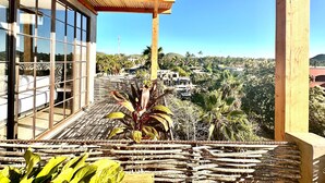 Een houten balkon met uitzicht op een woonwijk en palmbomen.