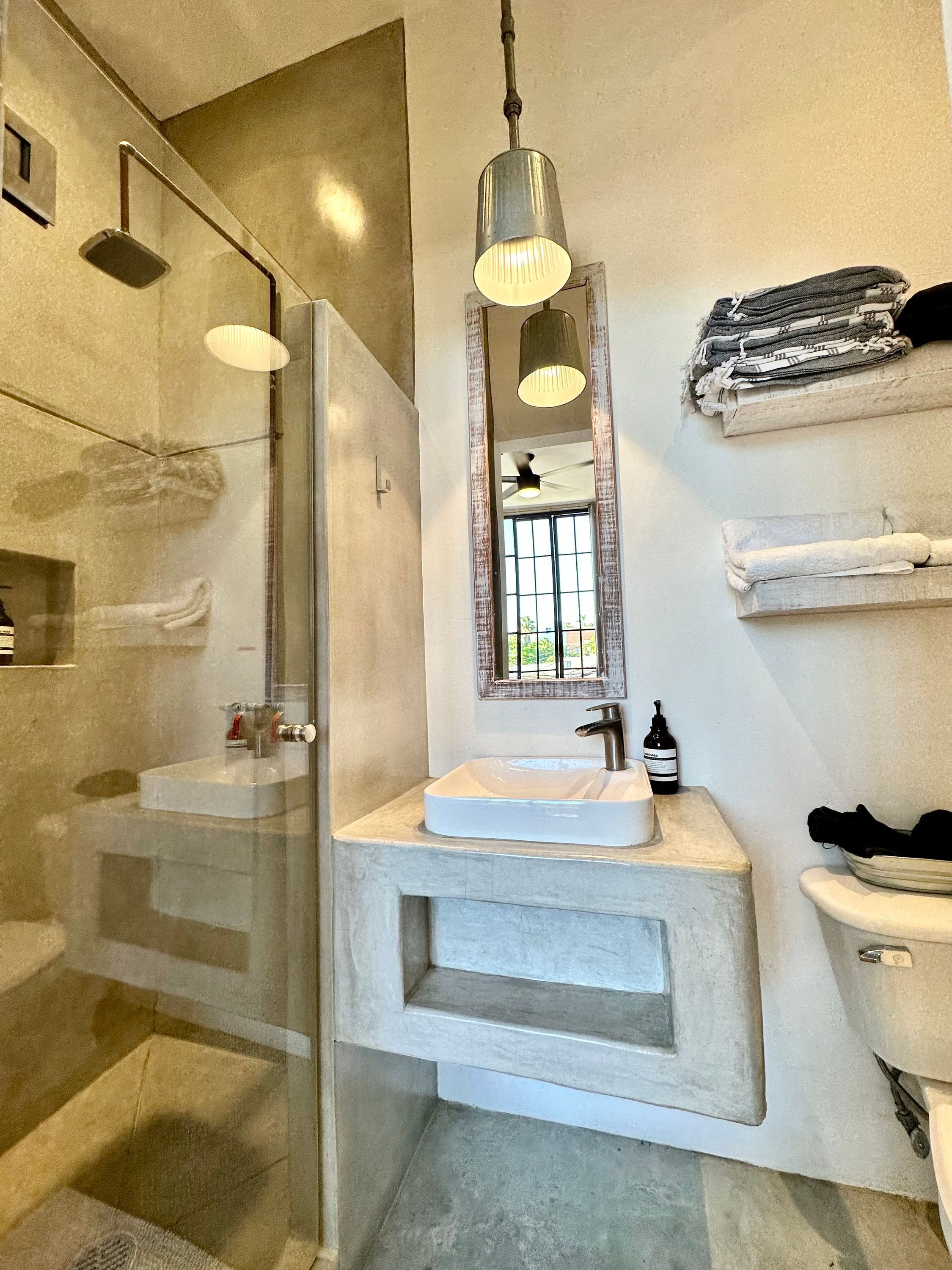A modern bathroom with a glass shower enclosure, a vanity with a large mirror, and a towel rack.