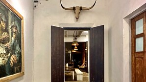 A hallway with a large bull's skull, a painting, and a wooden door. - TS3 Queen in Todos Santos (Todos Santos)
